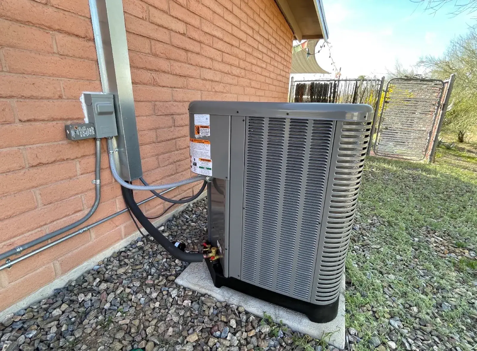 A clean AC condenser installed beside a brick Tucson home.